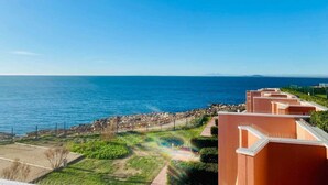 A coastal view with a clear sky, a beach, and a row of buildings with a paved walkway leading to the beach. - "578" Superb T2 Sea Front, Parking, Air Conditioning (Sète)