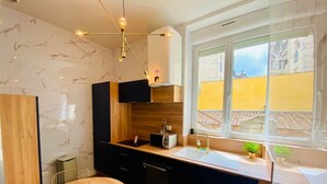 Una cocina moderna con paredes de mármol, encimera de madera y ventana con vistas a edificios.