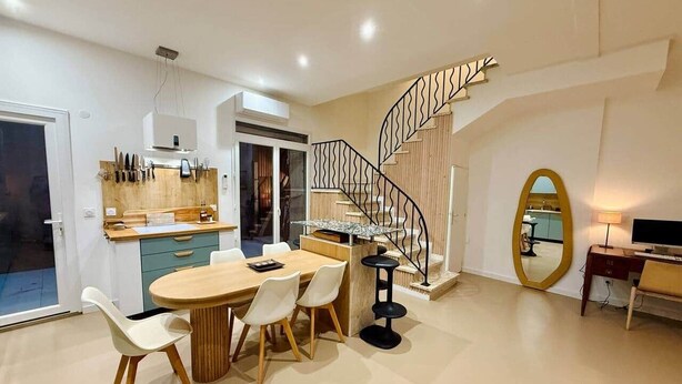 Una cocina moderna con comedor, una escalera espiral y un espejo grande.