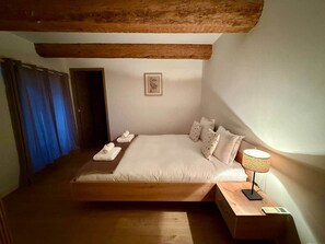 Une chambre à coucher avec un lit en bois, une table de chevet avec une lampe et un tableau encadré au mur.