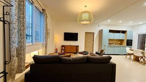 Una sala de estar moderna con un sofá, un televisor y un comedor con sillas y una mesa.