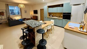 Una cocina moderna con una isla central, taburetes de bar, una mesa de comedor y armarios azul claro.