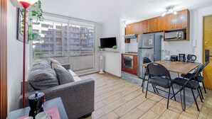 A compact apartment with a kitchenette, a dining area, a sofa, and a large window. - Live Downtown 2BR Apartment W/ 2 TV near Downtown (Santiago)