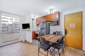Eine kompakte Küche mit Holzschränken, einem Kühlschrank, einer Mikrowelle und einem Esstisch mit Stühlen.