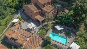 An aerial view of a property with a swimming pool, terracotta-tiled buildings, and surrounding greenery. - Podere Bagnoli farmhouse with swimming pool and sea view (Toscana)