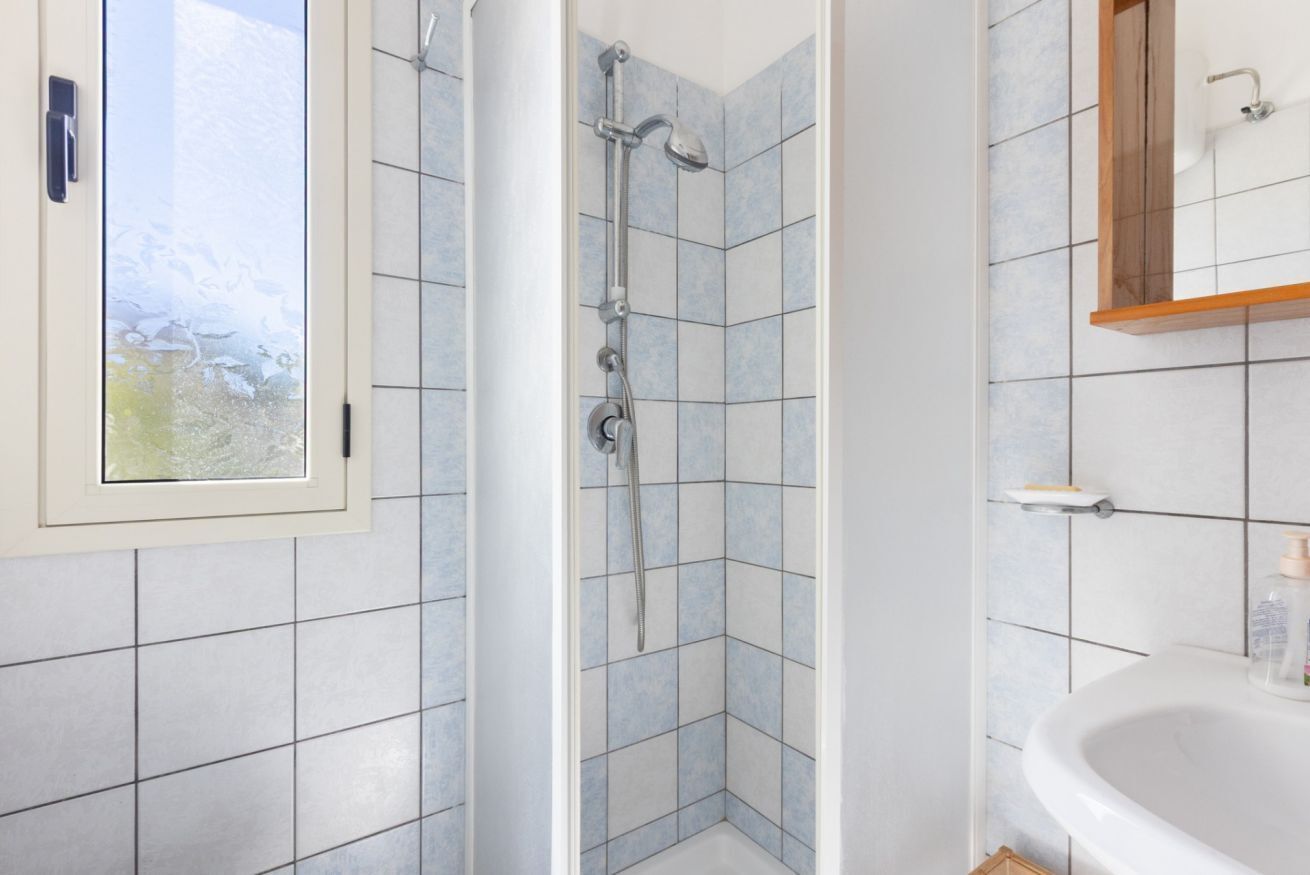 Une salle de bain avec une douche, un lavabo et une fenêtre.