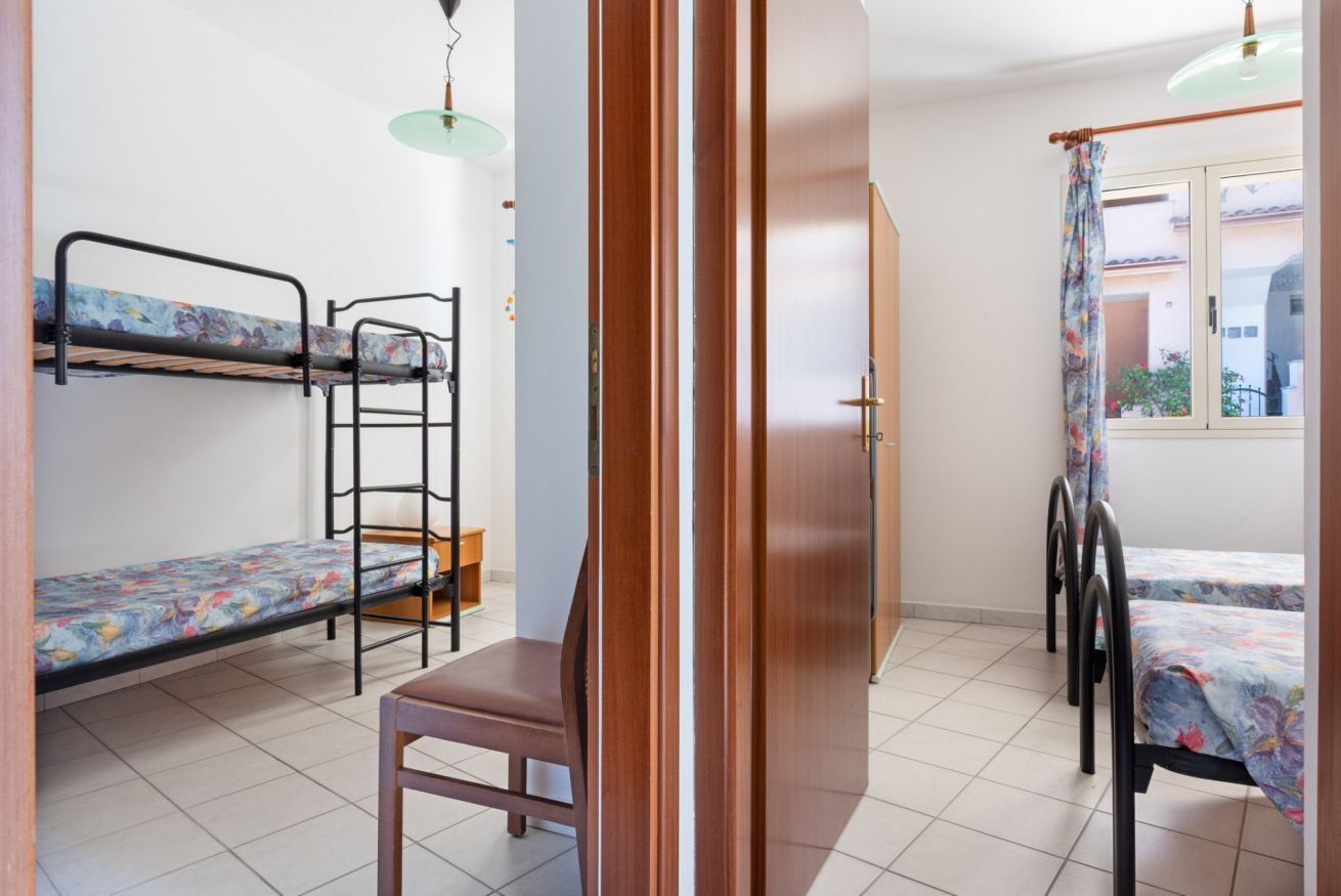 Un dormitorio con literas, una silla de madera, una puerta y una ventana.