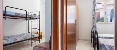 Un dormitorio con literas, una silla de madera, una puerta y una ventana.