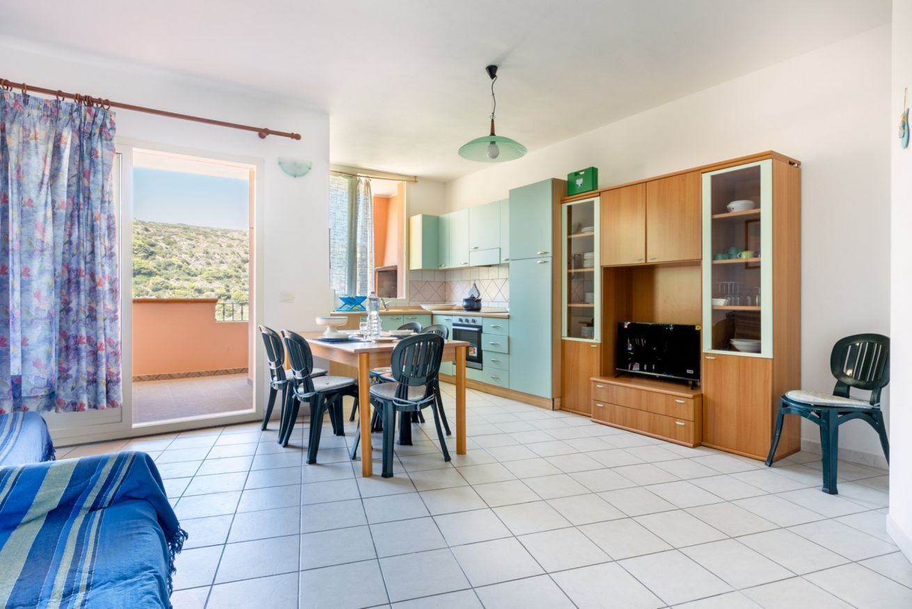 Un espacio habitable compacto con comedor, kitchenette y vista al exterior.