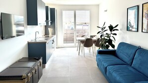 Ett kompakt bostadsutrymme med ett litet kök, en matplats och en soffa.