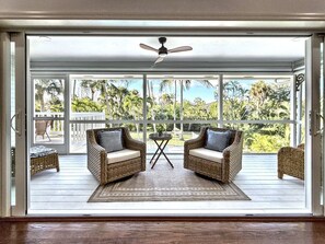 Una habitación amplia con dos sillones de mimbre, una mesita y un ventilador de techo.