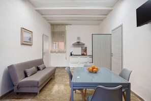 Un espace de vie compact comprenant un canapé, une table à manger et un coin cuisine.