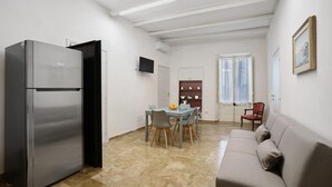 A compact kitchen with a refrigerator, dining table, chairs, and a sofa. - Apartment 'Superior  Il Cortiletto 21' with Shared Terrace, Wi-Fi and Air Conditioning (Marsala)