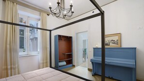 A bedroom with a bed, a wardrobe, a mirror, a chandelier, and a piano. - Apartment 'Superior  Il Cortiletto 21' with Shared Terrace, Wi-Fi and Air Conditioning (Marsala)