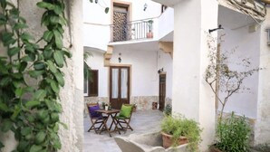 A courtyard with a table and chairs, potted plants, and a door. - Apartment 'Superior  Il Cortiletto 21' with Shared Terrace, Wi-Fi and Air Conditioning (Marsala)