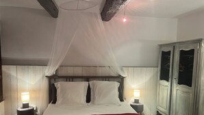 Ein Schlafzimmer mit Baldachinbett, zwei Nachttischlampen, einem Kleiderschrank und einer roten Bettdecke.
