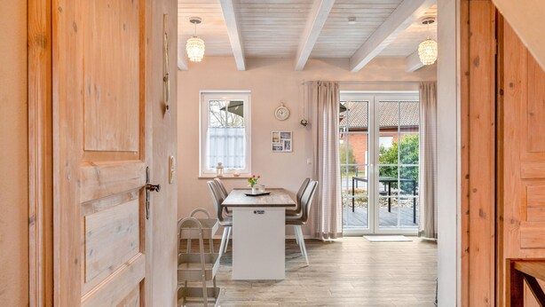 Un intérieur en bois comprenant un coin repas, un escalier et une vue à travers une porte vitrée.