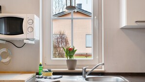 A kitchen with a microwave, sink, and window with a view of a building. - Swedish House Zierow - Baltic Sea - House 23b (Zierow)