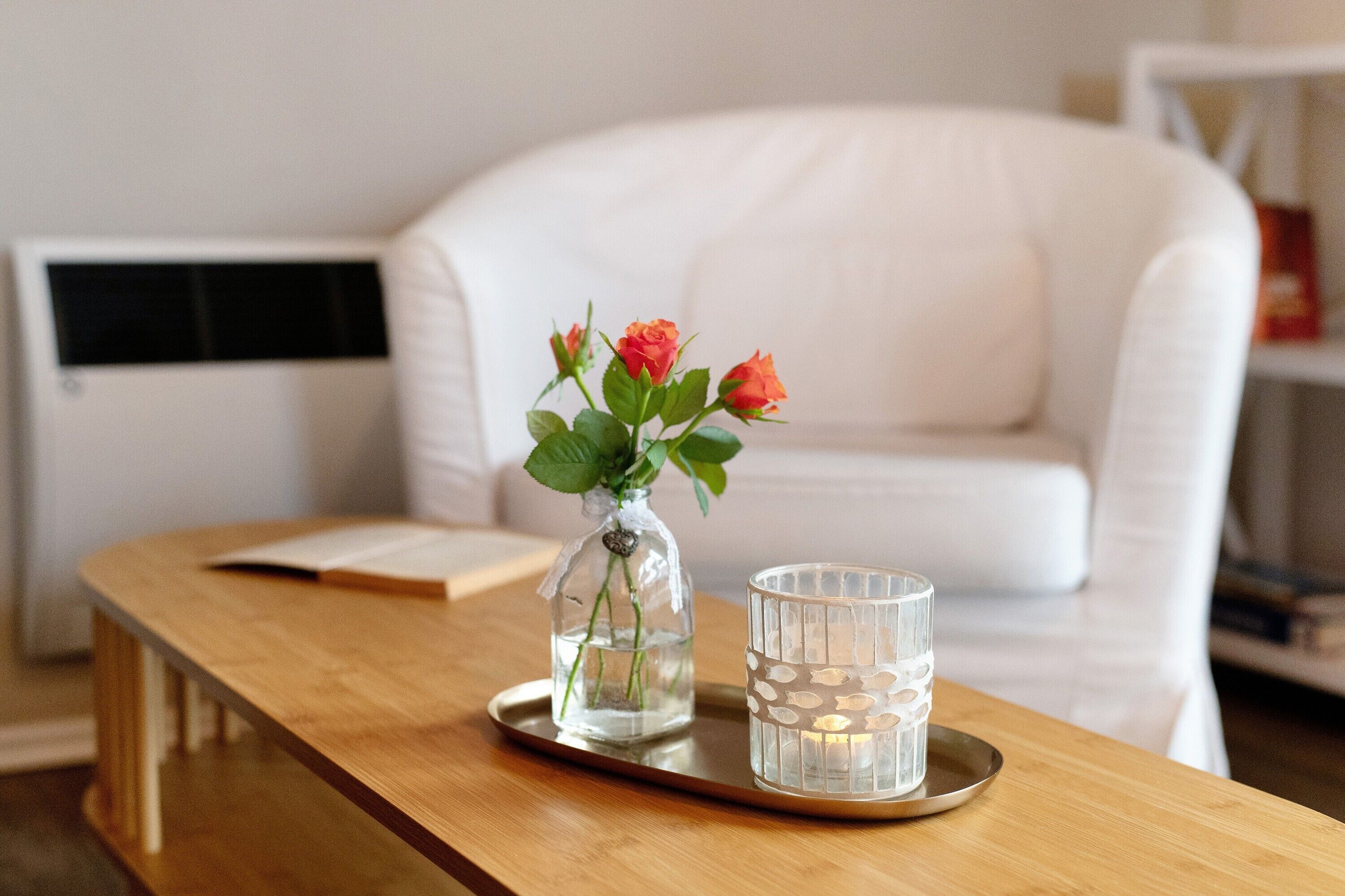 Une table en bois sur laquelle se trouve un vase en verre contenant des fleurs et un chandelier.
