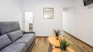 Un salon moderne avec un canapé gris, une table basse en bois et deux plantes en pot.