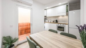 Une cuisine moderne avec des meubles blancs, une table à manger en bois et des chaises vertes.
