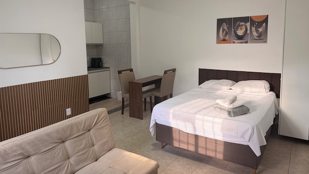 A hotel room with a bed, a sofa, a desk, and a kitchenette. - Private studio apartment with Smart TV and air conditioning. (Belo Horizonte)