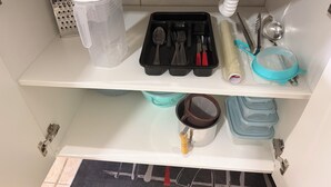 A kitchen shelf with a water dispenser, a grater, a black utensil holder, a blue strainer, and a pot. - Private studio apartment with Smart TV and air conditioning. (Belo Horizonte)
