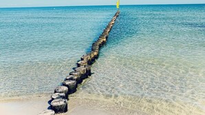 A clear view of a wooden jetty extending into the water with a flag at the end. - Holiday Home 'Idyllisches Reethaus in Strandnähe' with Shared Terrace, Private Garden and Wi-Fi (Fuhlendorf)