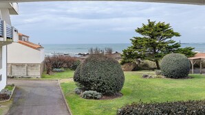 Vue d’une propriété située sur la côte, avec une allée pavée, une pelouse bien entretenue et un grand conifère.