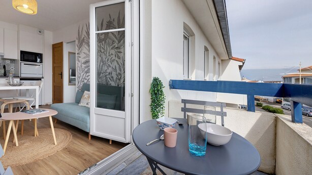Un balcon avec une table à manger, des chaises et une vue sur la rue.