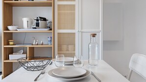 Une table à manger avec des assiettes, des verres et une bouteille, entourée d’étagères en bois où sont disposés divers objets.