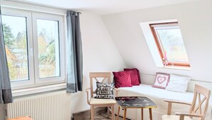 Une pièce comprenant un lit, une petite table, deux chaises, un canapé, une fenêtre avec des rideaux et un radiateur.
