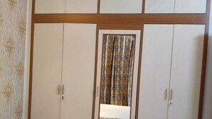 A bedroom with a large bed, a wardrobe with multiple compartments, and a mirror.