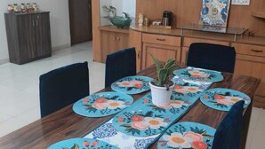A dining area with a wooden table set with blue placemats featuring floral designs, surrounded by chairs.