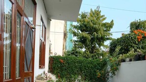 A small patio with artificial grass, wicker furniture, and potted plants.