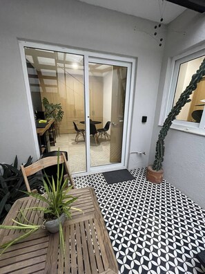 A room with a wooden table and chairs, a potted plant, and a patterned floor.