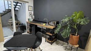Eine moderne Küche mit dunkler Wand, einem Holztisch, schwarzen Stühlen und einem Blumentopf.
