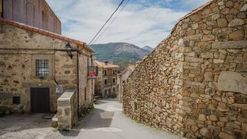 Eine enge Straße mit Steinhäusern, einer sichtbaren Tür und einem Berg im Hintergrund.