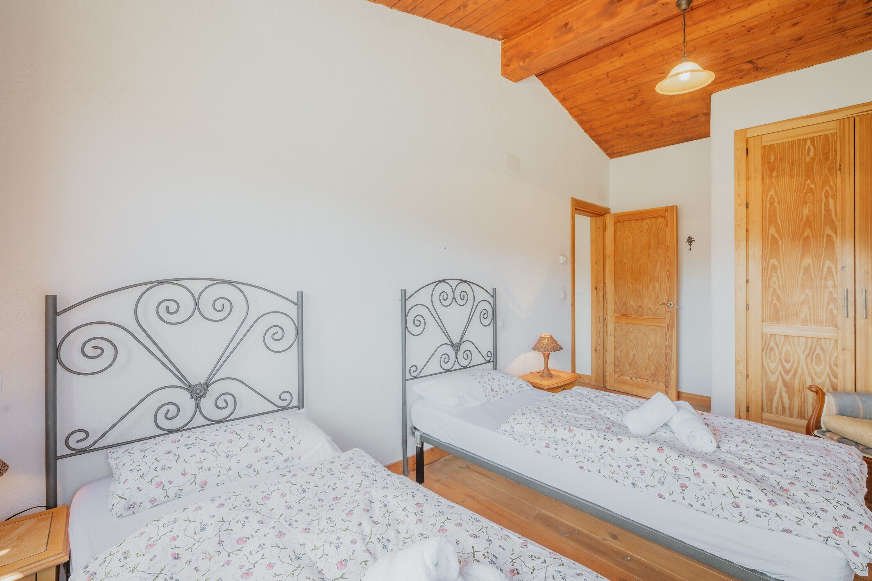 Une chambre avec deux lits, un plafond en bois et une porte en bois.