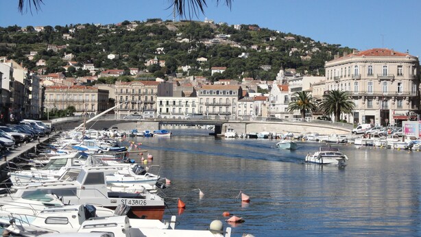 Un port de plaisance avec des bateaux amarrés, un pont et des bâtiments en arrière-plan.