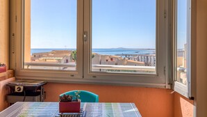 Une pièce avec une grande fenêtre, une table sur laquelle est posée une carte, une chaise et une petite table avec une plante.