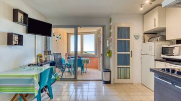 Una cocina con comedor, televisor y vista por un ventanal.