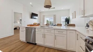 Una cocina moderna con armarios blancos, lavavajillas y una isla grande con asientos.