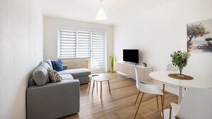 Una sala de estar moderna con un sofá, una mesita redonda y un televisor.