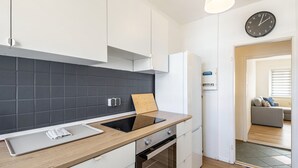 Una cocina moderna con salpicadero negro, armarios blancos, encimera de madera y horno empotrado.