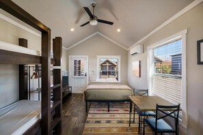 A bedroom with a bed, a desk, and a chair, a ceiling fan, and a window with blinds. - HTR Moab (Moab)