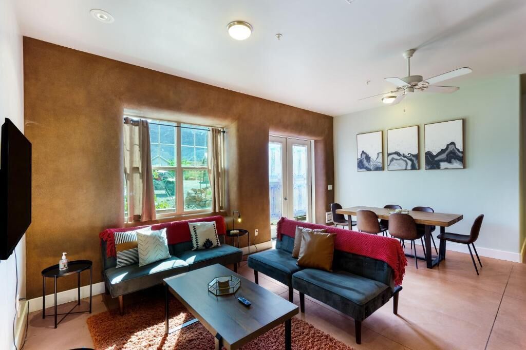 A living room with a sofa, coffee table, and dining area with chairs.