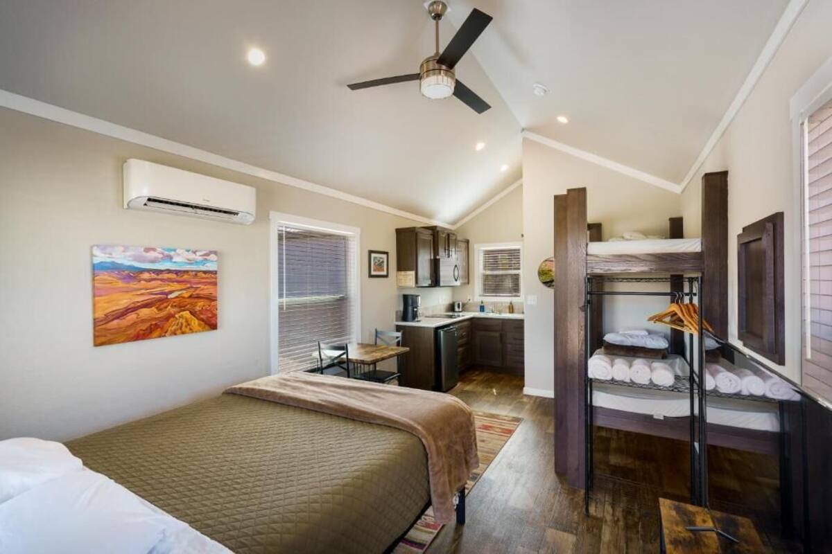A compact hotel room with a bed, a kitchenette, and a small dining area.