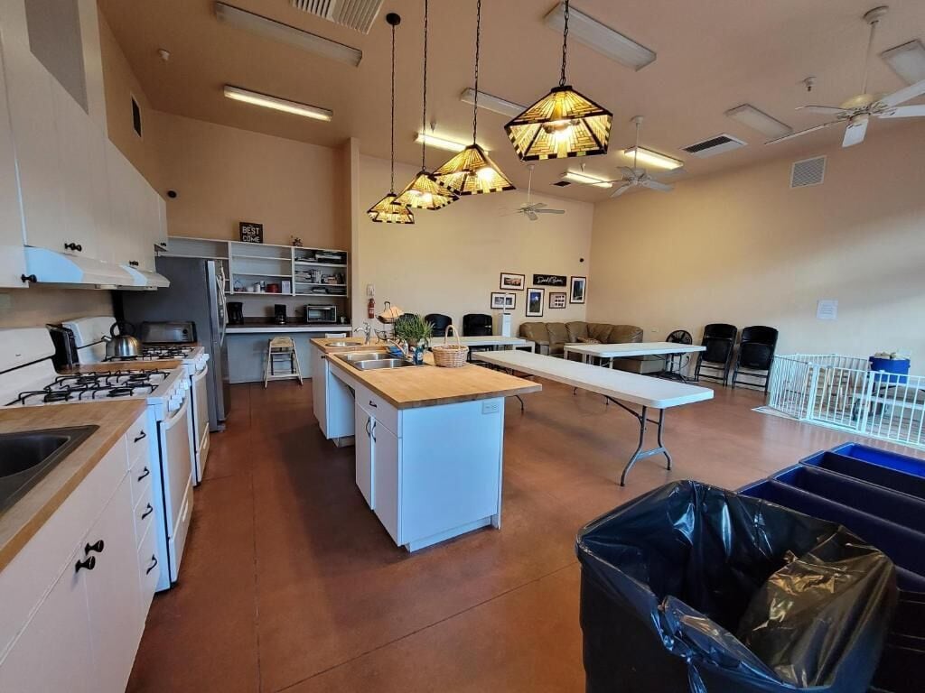 A spacious kitchen with a central island, white cabinets, and a dining area with a long table.