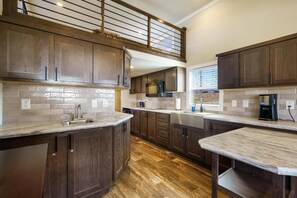 A kitchen with dark wood cabinets, a marble countertop, and a built-in microwave. - HTR Moab (Moab)